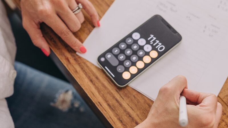 A person adding up and tracking their expenses with a calculator.