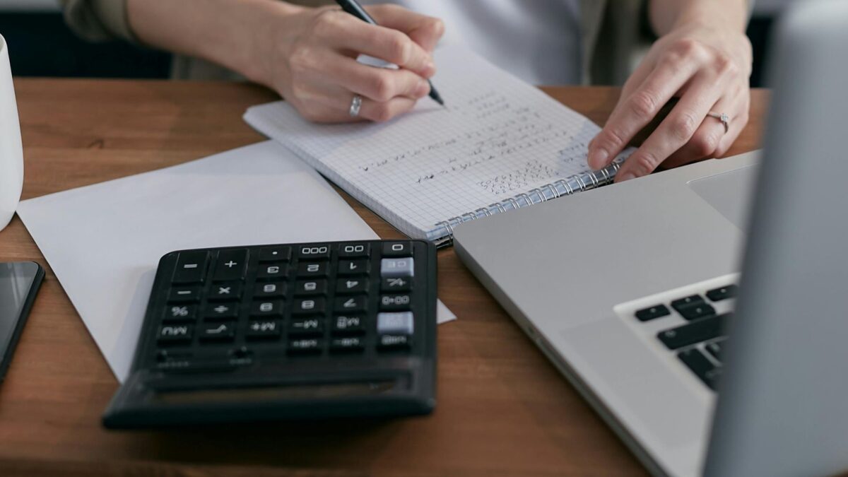 Image of a calculator and budget with woman writing her layoff plan