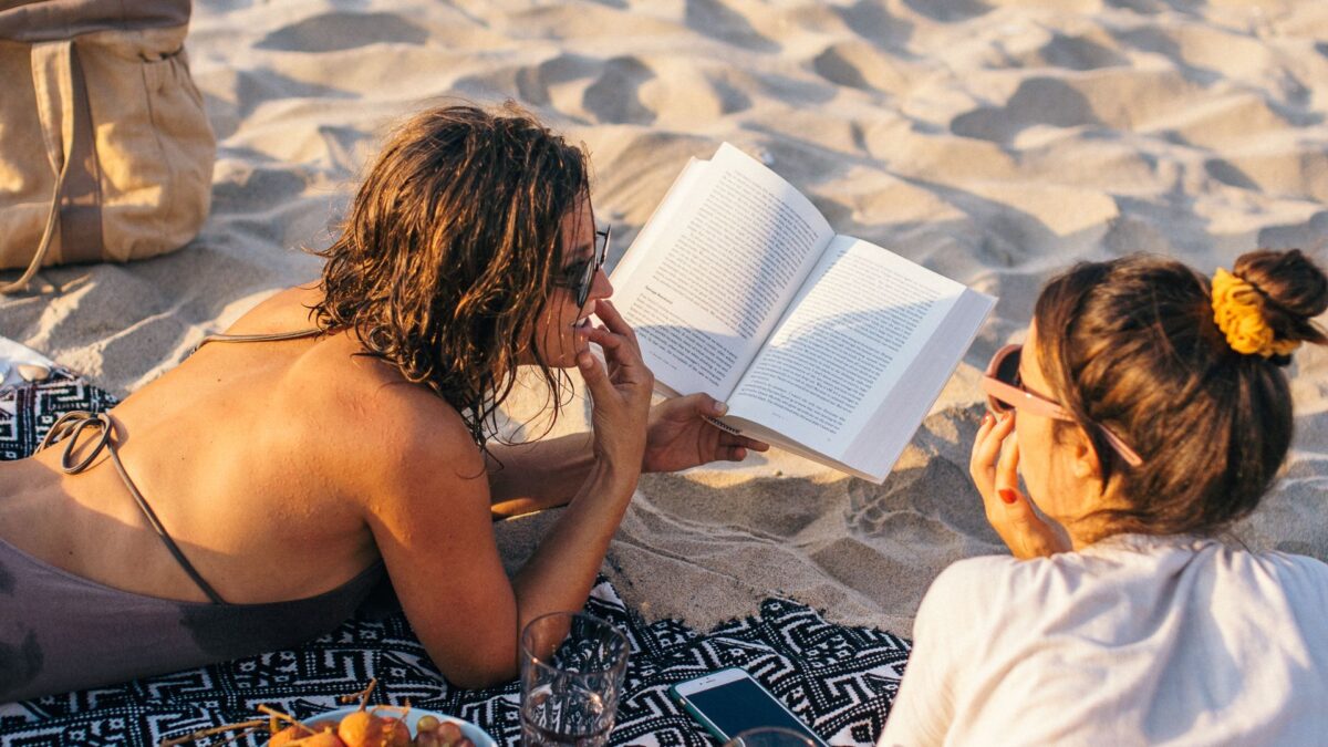 Image of women reading a financial book on the beach